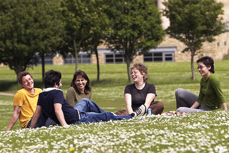 Students sat on grass on a sunny day